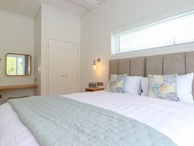 A bedroom with a bed a headboard two pillows a wall light a closet and a mirror at Hawthorn Croft in Haverthwaite
