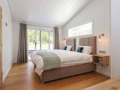 A bedroom with two single beds pushed together next to a sliding glass door at Hawthorn Croft in Haverthwaite