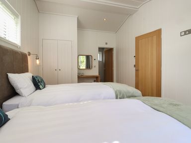 A bedroom with two single beds a wooden door a wardrobe and a wall-mounted mirror at Hawthorn Croft in Haverthwaite