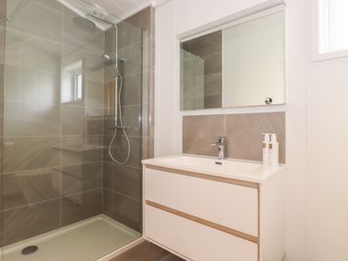 A bathroom with a walk in shower and a sink with a mirror at Hawthorn Croft in Haverthwaite