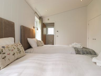 A bedroom with two single beds with floral cushions and folded towels at Ash Thwaite in Haverthwaite