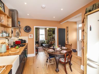 A kitchen with wooden countertops and a dining table set with plates and glasses at The Corner House in Weymouth