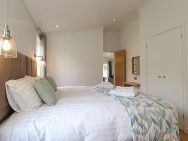 A bedroom with a bed linens pillows folded towels and a floral blanket at The Brambles in Haverthwaite