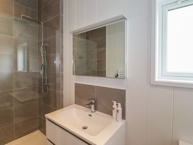 A bathroom with a shower, sink, mirror, and window at The Brambles in Haverthwaite