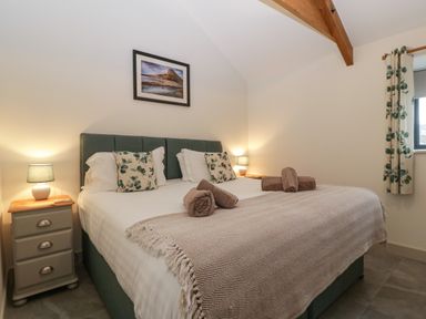 A bedroom with a double bed two bedside tables lamps and a window with curtains at The Byre in St Brides Major