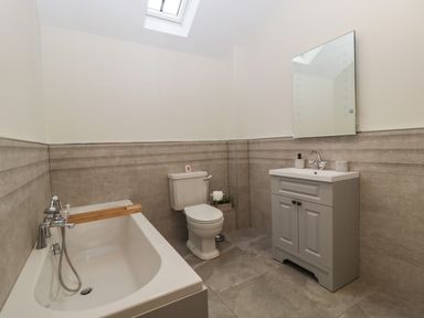 A bathroom with a bathtub a toilet and a sink with a mirror at The Byre in St Brides Major