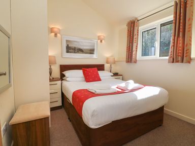A bedroom with a double bed bedside tables and a window at Chalet Log Cabin C11 in Combe Martin