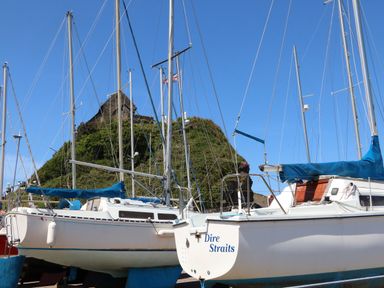 Sailboats docked with a grassy hill and a stone building behind at Chalet Log Cabin C8 in Combe Martin