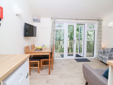 A dining area with wooden table and chairs next to glass doors leading to a balcony at Chalet Log Cabin C8 in Combe Martin