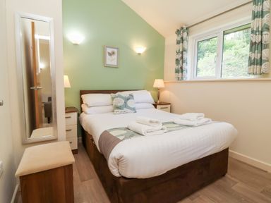 A bedroom with a double bed two bedside tables and a window at Chalet Log Cabin C8 in Combe Martin
