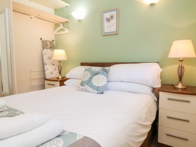 A bedroom with a double bed bedside tables lamps and an ironing board at Chalet Log Cabin C8 in Combe Martin