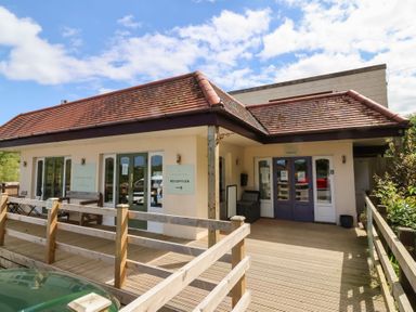 A building with a wooden deck and signs for reception and check in at Chalet Log Cabin C8 in Combe Martin