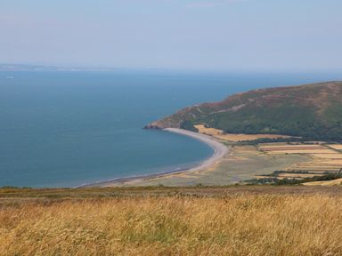 A coastal landscape view with a curved beach grassy fields and hills at Chalet Log Cabin C9 in Combe Martin