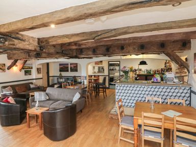 A lounge area with sofas and armchairs wooden tables and a bar with bottles and flowers at Chalet Log Cabin C9 in Combe Martin
