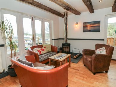 A living room with leather armchairs a wood burning stove and a wooden coffee table at Chalet Log Cabin C9 in Combe Martin