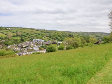 A grassy field overlooking a village with houses and rolling green hills in the background at Chalet Log Cabin C9 in Combe Martin