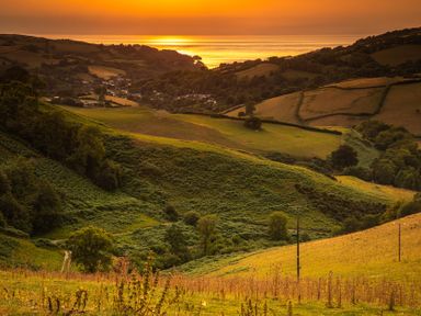 A scenic view of hills and fields at sunset at 9 Manleigh Park in Combe Martin