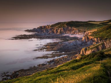 A coastline with cliffs and a lighthouse at 9 Manleigh Park Combe Martin