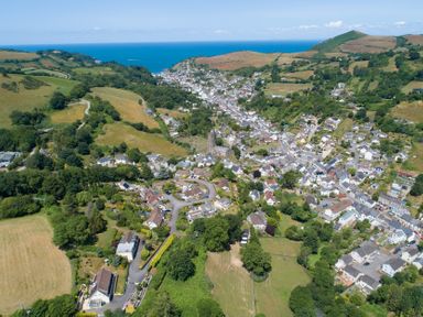 An aerial view of a village with houses and fields near the sea at 9 Manleigh Park in Combe Martin