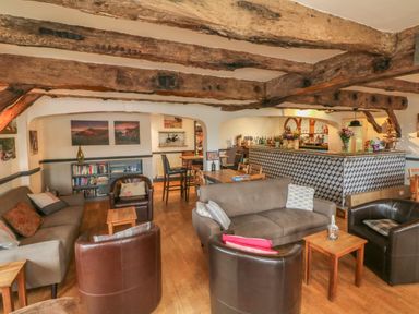 A lounge area with sofas chairs tables a bar and wooden ceiling beams at Chalet Log Cabin L3 in Combe Martin