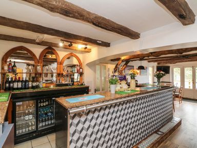 An interior bar area with wooden beams on the ceiling bottles glasses and flowers on the counter at Chalet Log Cabin L6 in Combe Martin