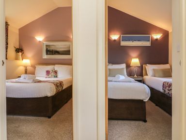Two bedrooms with beds bedside lamps and wall art at Chalet Log Cabin L10 in Combe Martin