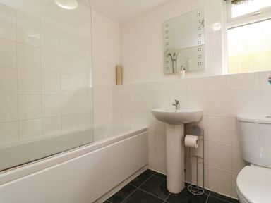 A bathroom with a bathtub shower combination sink toilet and a window at Chalet Log Cabin L10 in Combe Martin