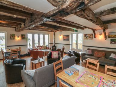 A sitting room with wooden beams a puzzle on a table and multiple chairs and sofas at Chalet Log Cabin L10 in Combe Martin