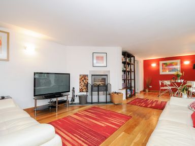 A living room with a fireplace a television and two white sofas at Great Brightor Cob Barn in St Kew Highway