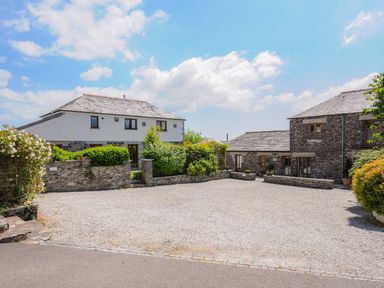 Two stone and white houses with gravel driveway and green bushes at Great Brightor Cob Barn in St Kew Highway