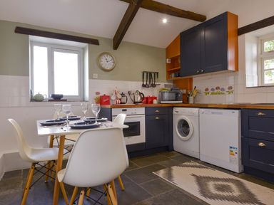 A kitchen with dining table set for four and appliances at Great Brightor Cob Barn in St Kew Highway