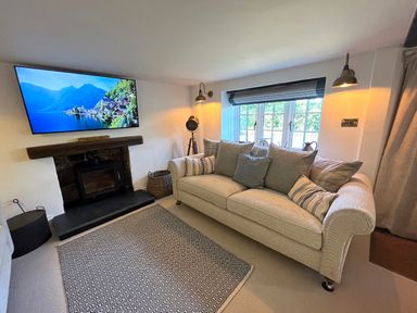 A living room with a sofa cushions carpet and wall mounted television at Old Post Office in Sherborne