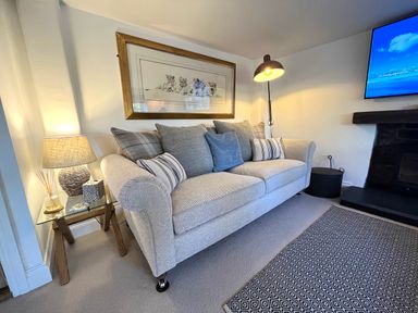 A living room with a sofa pillows a table lamp a framed picture on the wall and a fireplace at Old Post Office Sherborne