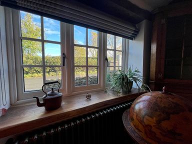 A window with a teapot clock and plant on the wooden sill and a globe in the corner at Old Post Office Sherborne