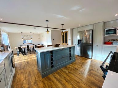 A kitchen with an island in the center and a dining table with chairs in the background at Old Post Office in Sherborne