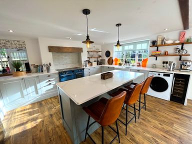 A kitchen with an island and three brown bar stools at Old Post Office in Sherborne