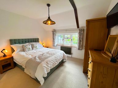 A bedroom with a double bed bedside tables wardrobe and dresser at Old Post Office in Sherborne