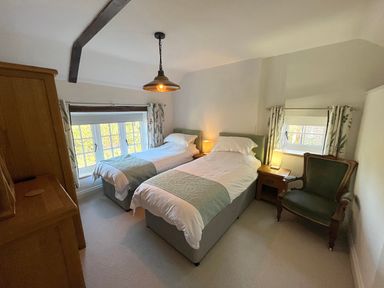 A bedroom with two single beds beside windows and a wooden chair at Old Post Office in Sherborne