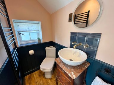 A bathroom with a toilet basin on a marble top vanity and a round mirror at Old Post Office in Sherborne