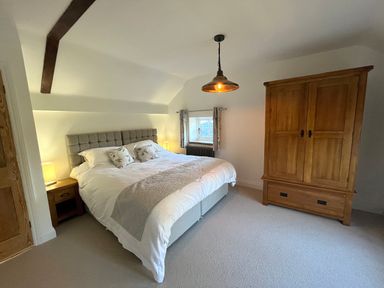 A bedroom with a double bed bedside tables and a wooden wardrobe at Old Post Office in Sherborne
