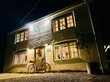 A two story building with lit windows a bicycle near the entrance and a potted plant at Old Post Office in Sherborne