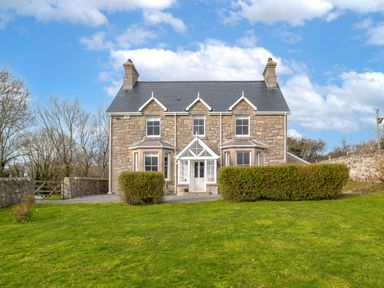 A stone house with a slate roof and a green lawn in front at Flagstaff in Penmon near Beaumaris