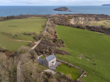 A house with a walled garden near green fields a road trees and an island in the sea at Flagstaff in Penmon near Beaumaris
