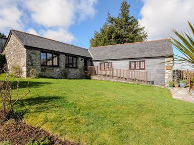 A stone and slate cottage with windows and a lawn in front at Mums Cottage in Minions near Upton Cross