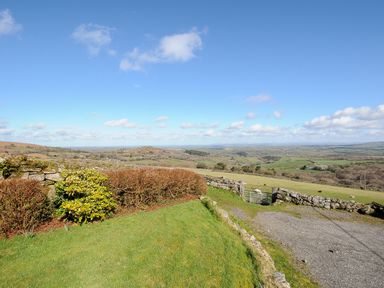 A rural landscape with a stone wall hedge and green fields under a blue sky at Bickle Bice Cottage in Minions near Liskeard