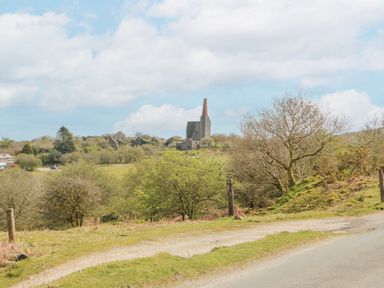 A rural landscape with a road trees and an old industrial building with a chimney at Bickle Bice Cottage in Minions near Liskeard