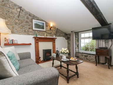 A living room with a grey sofa a fireplace and a wooden coffee table with flowers and snacks at Bickle Bice Cottage in Minions near Liskeard