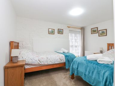 A bedroom with two single beds with blue blankets and floral bedding at Bickle Bice Cottage Minions near Liskeard