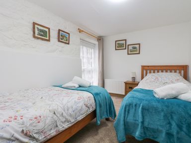A bedroom with two single beds covered in floral bedding and blue blankets at Bickle Bice Cottage in Minions near Liskeard