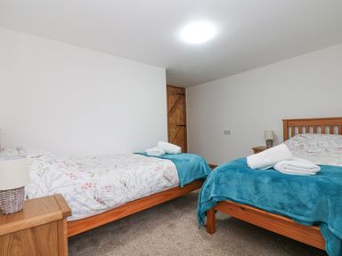 A bedroom with two single beds with blue blankets and white towels on them at Bickle Bice Cottage in Minions near Liskeard